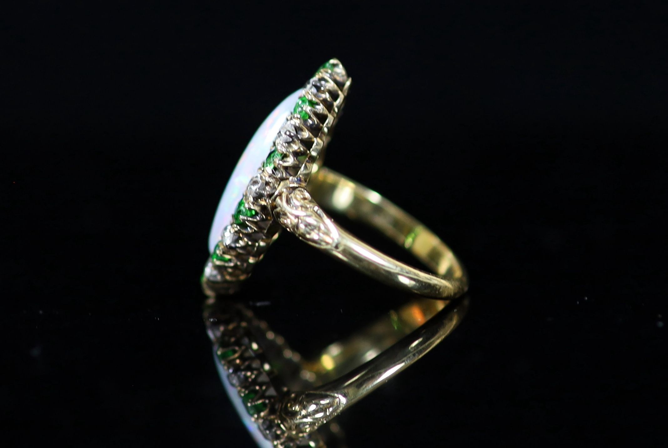 An early 20th century 18ct gold, white opal, green garnet and diamond set navette shaped dress ring